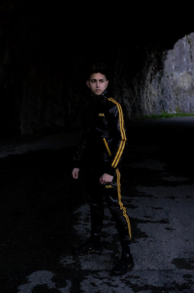 MR Riegillio PVC Tracksuit jacke mit gelben streifen von einem jungen gay getragen in schwarz glänzend mit passender hose von vorne