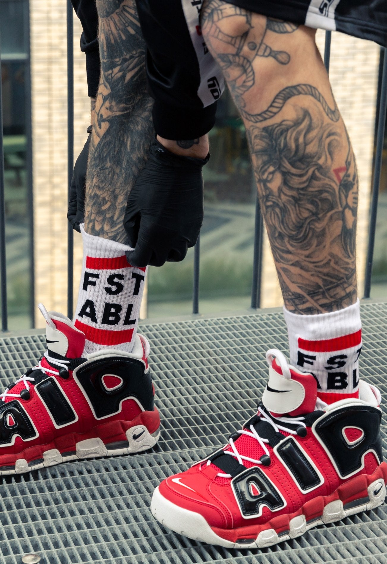 nahaufnahme von roten nike air max sneaker mit fst abl socks von sk8erboy an beinen mit tattoos